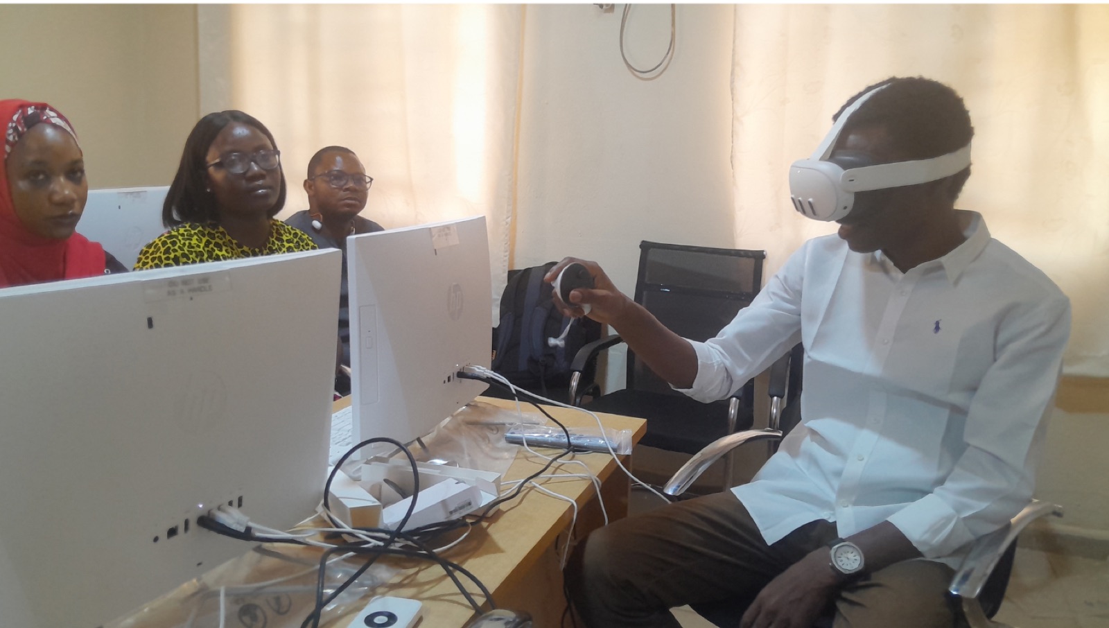 A participant wearing a VR headset at a desk while colleagues look on