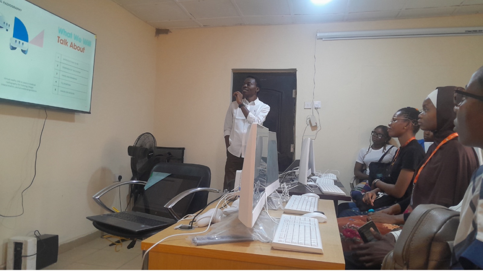 A speaker addressing seated participants during a training workshop
